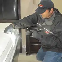 Bed bug inspection technician checking a mattress and bed frame for signs of infestation in Los Angeles, CA
