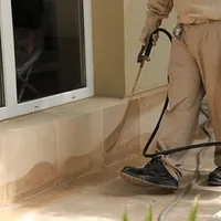 General pest control technician spraying exterior perimeter around a home in Los Angeles, CA