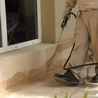 General pest control technician spraying exterior perimeter around a home in Los Angeles, CA