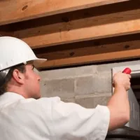 Termite inspection technician checking a basement wall and framing for termite activity in Los Angeles, CA