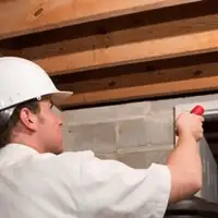 Termite inspection technician checking a basement wall and framing for termite activity in Los Angeles, CA